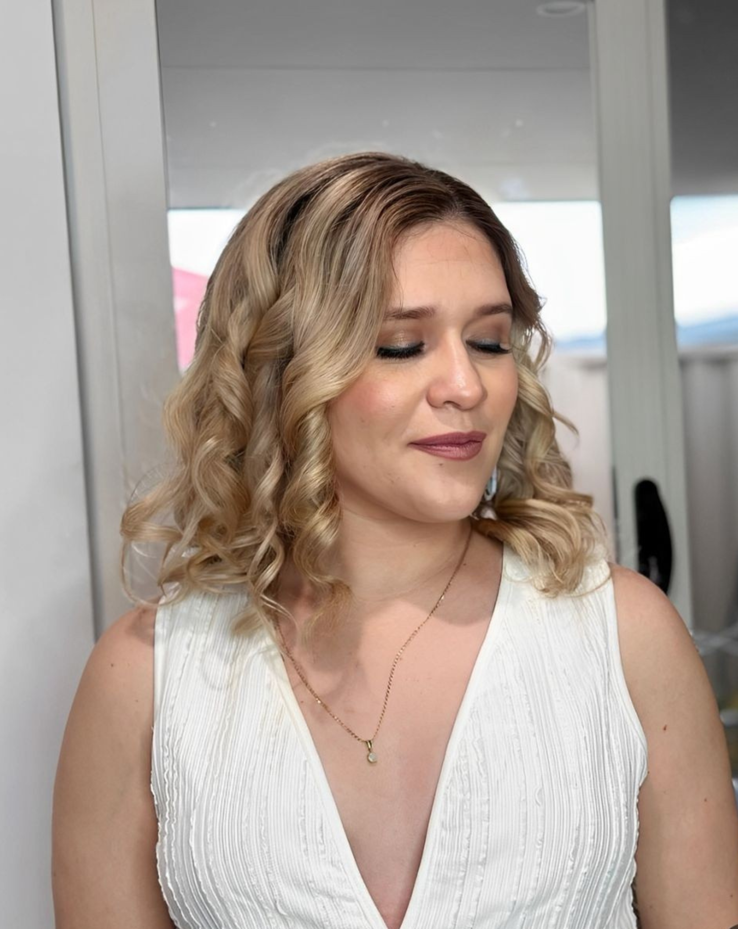 A woman dressed in white exuding elegance, with flawless makeup and a chic hairstyle, showcasing a stunning and graceful look.